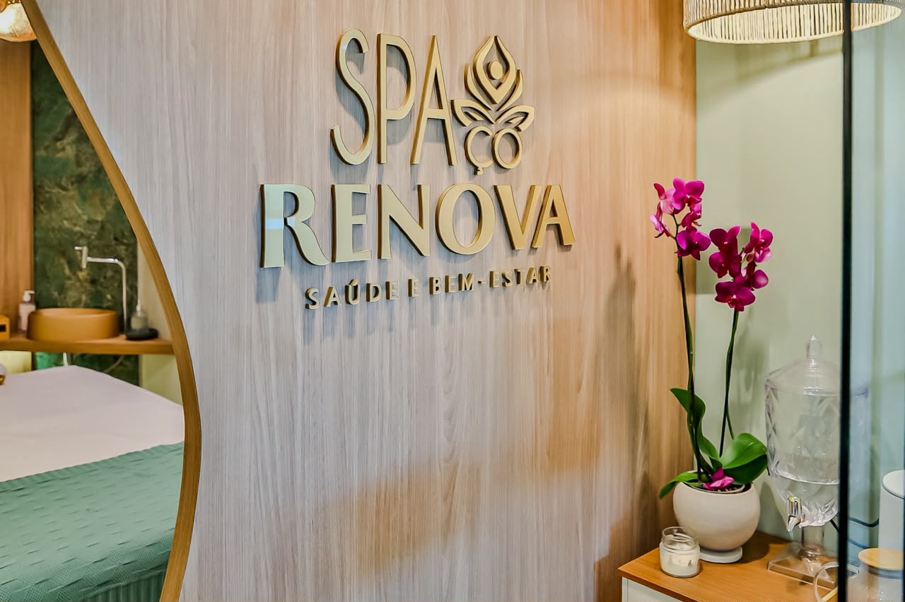 Logo do SPAçoRENOVA em dourado sobre parede de madeira